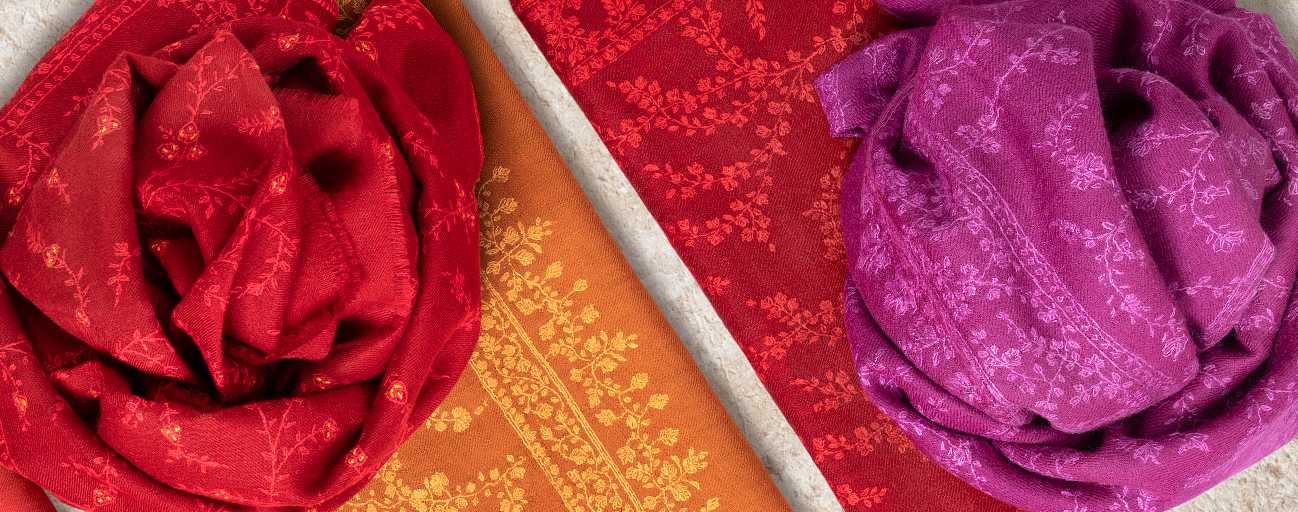 Embroidered pashmina shawls in reds, pinks and oranges.