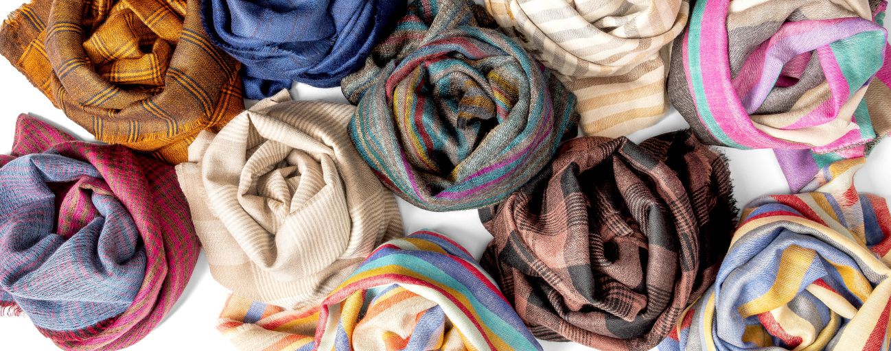 A collection of coiled pashmina shawls in checks and stripes.