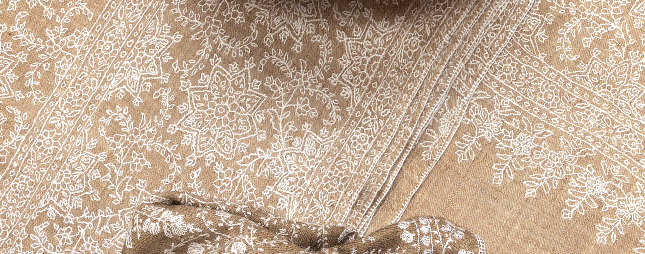 Detail from a beautifully embroidered blanket sized pashmina shawl in undyed brown and white.